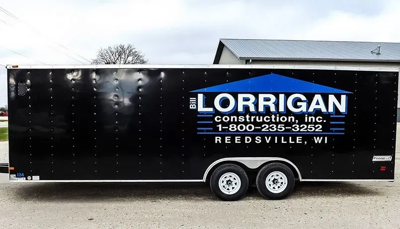 A lorrigan construction trailer is parked in front of a building