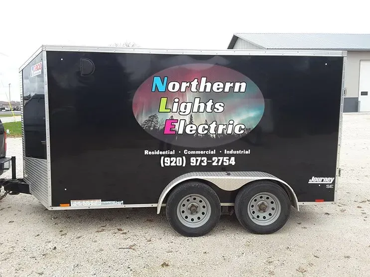 A trailer for northern lights electric is parked in a gravel lot.