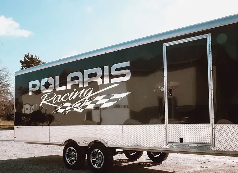 A polaris racing trailer is parked in a parking lot