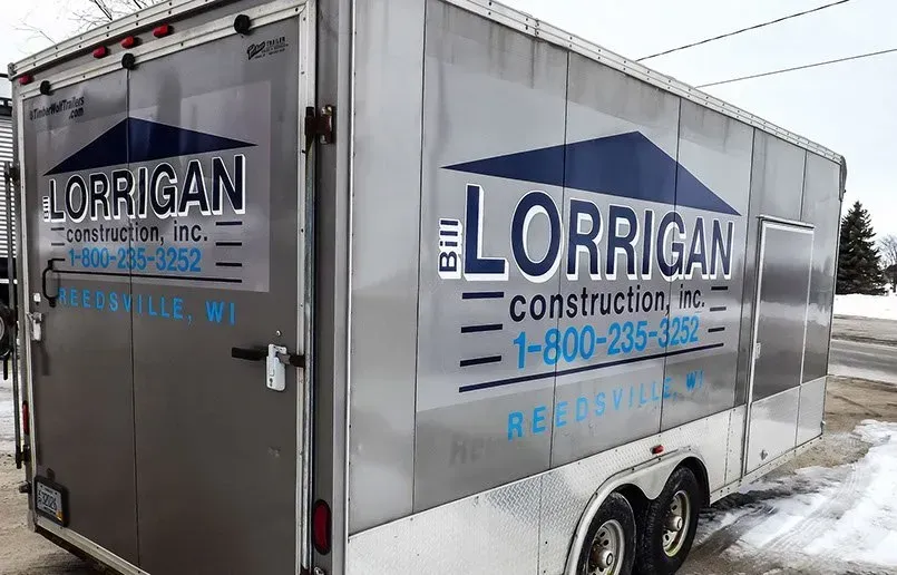 A lorrigan construction trailer is parked on the side of the road.