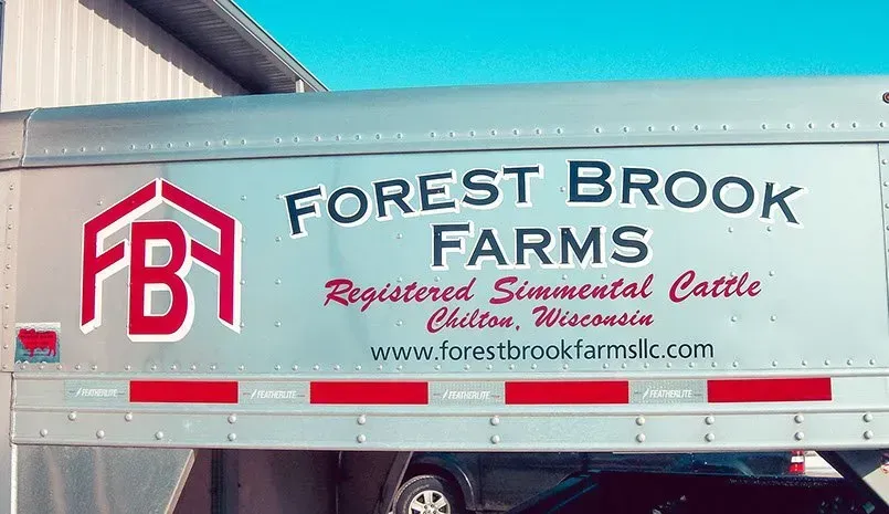 A forest brook farms trailer is parked in front of a building.