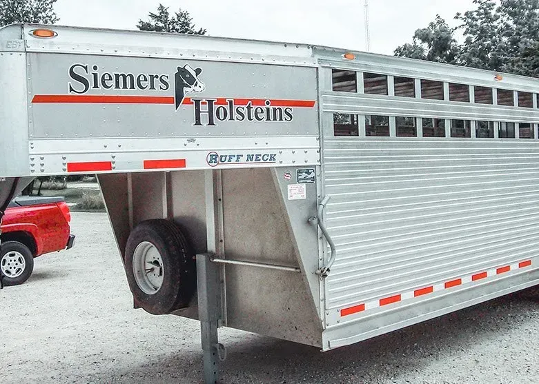 A silver trailer that says ' siemens holsteins ' on it