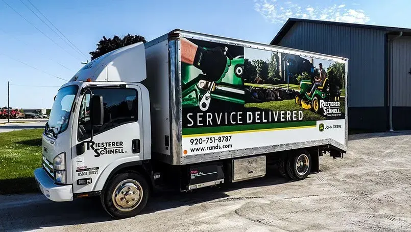 A service delivered truck is parked in front of a building.