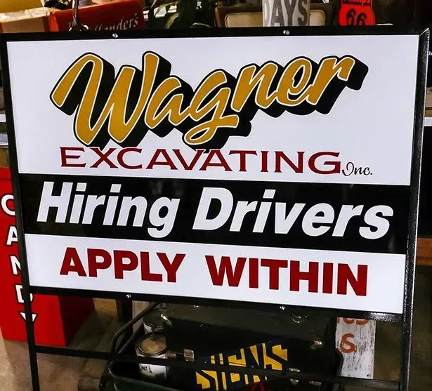 A sign for wagner excavating hiring drivers apply within
