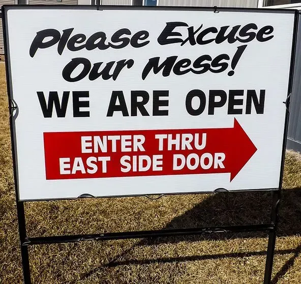 A sign that says please excuse our mess we are open