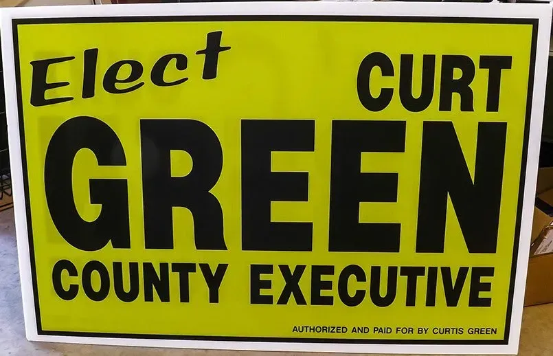 A yellow sign that says elect curt green county executive