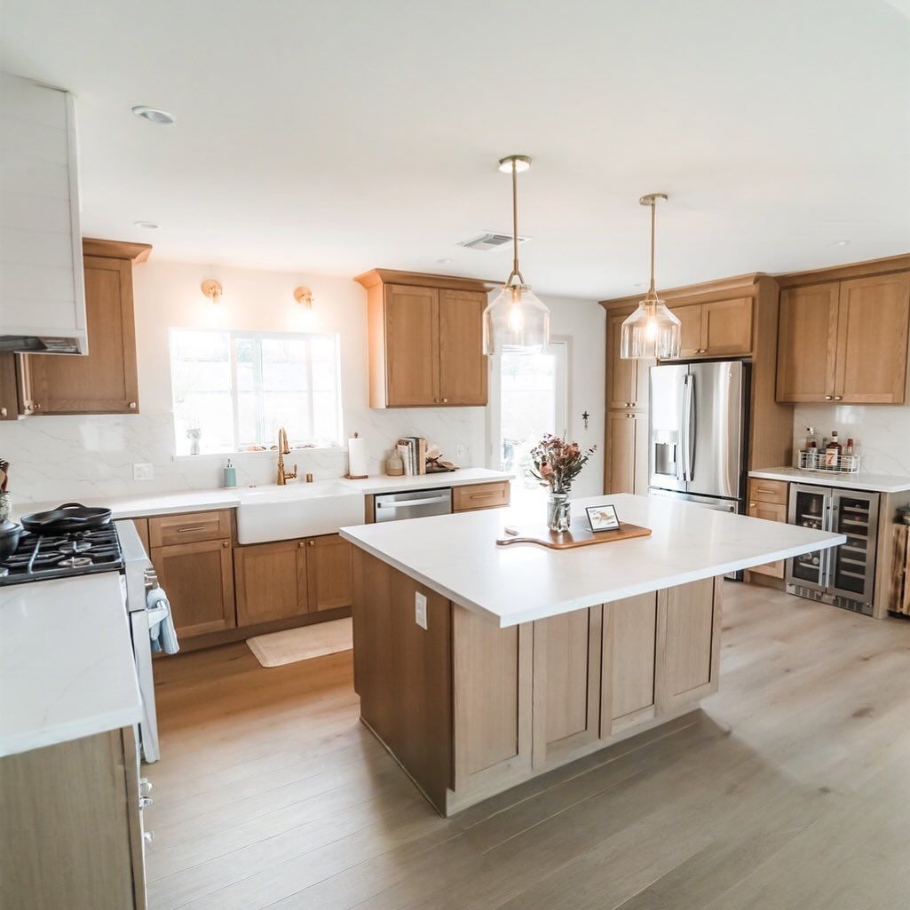 Bright, modern kitchen with wooden cabinets, white countertops, and a large island.
