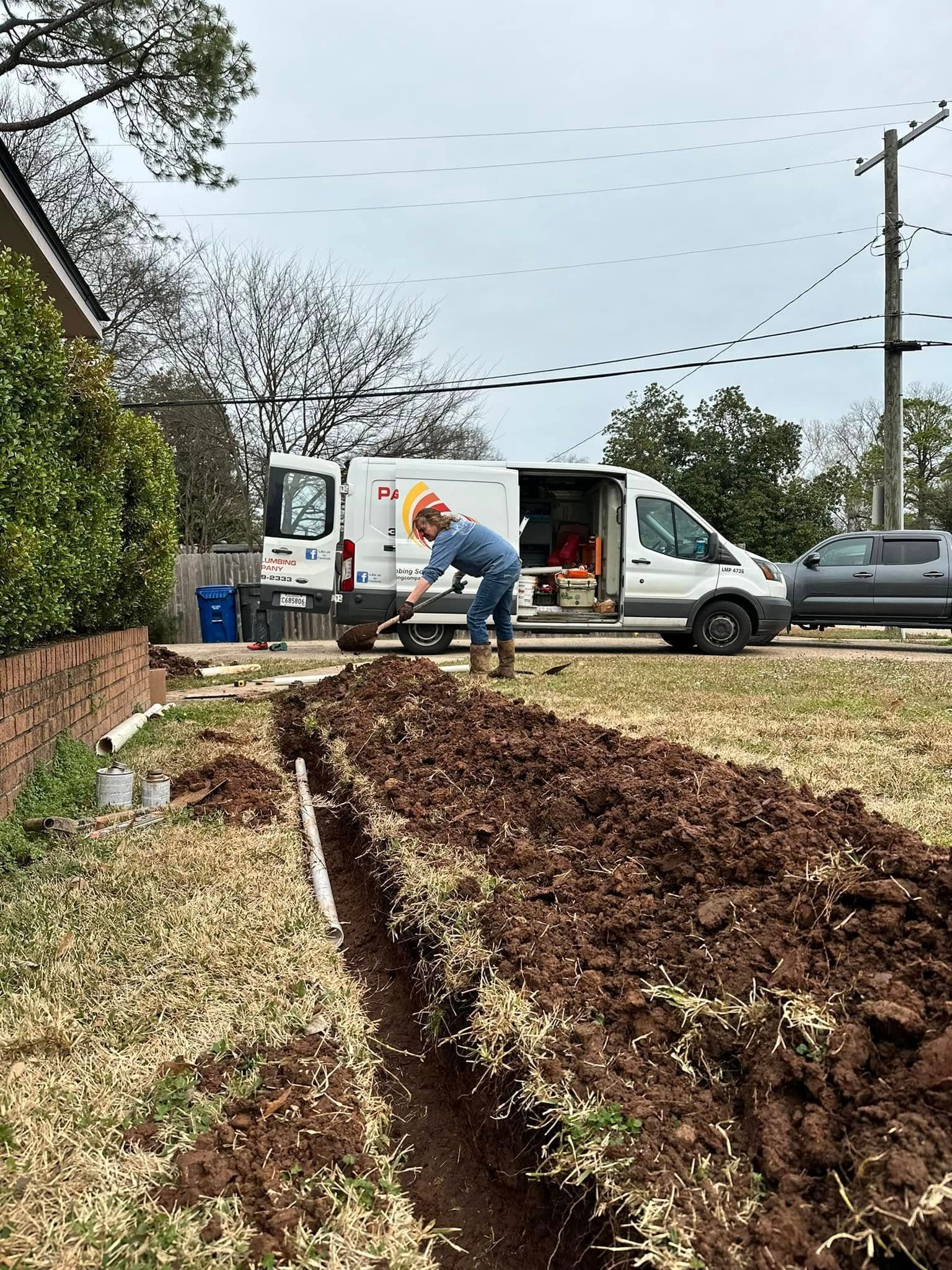 Worker loading a white van beside a long garden bed with brown mulch in a yard