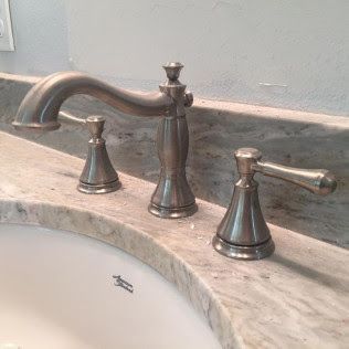 Bronze bathroom faucet set over a white sink with matching hot and cold handles