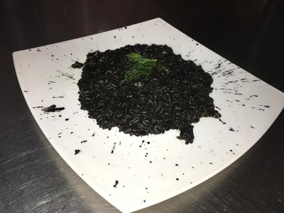Un cumulo nero di terra sciolta o pacciame su un telo bianco, con un piccolo germoglio verde al centro.