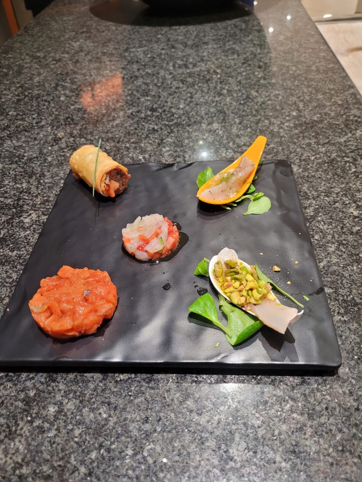 Vari pezzi di sushi disposti su un piatto di ardesia nera su un piano di lavoro.