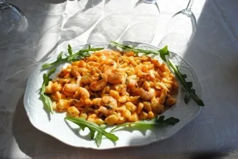 Pasta servita in un piatto con cremosa salsa all'arancia e guarnita con rucola, su una tovaglia bianca.