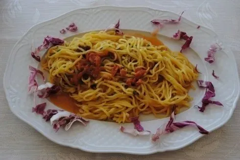 Piatto di spaghetti al sugo rosso, guarniti con cavolo viola su un piatto bianco.