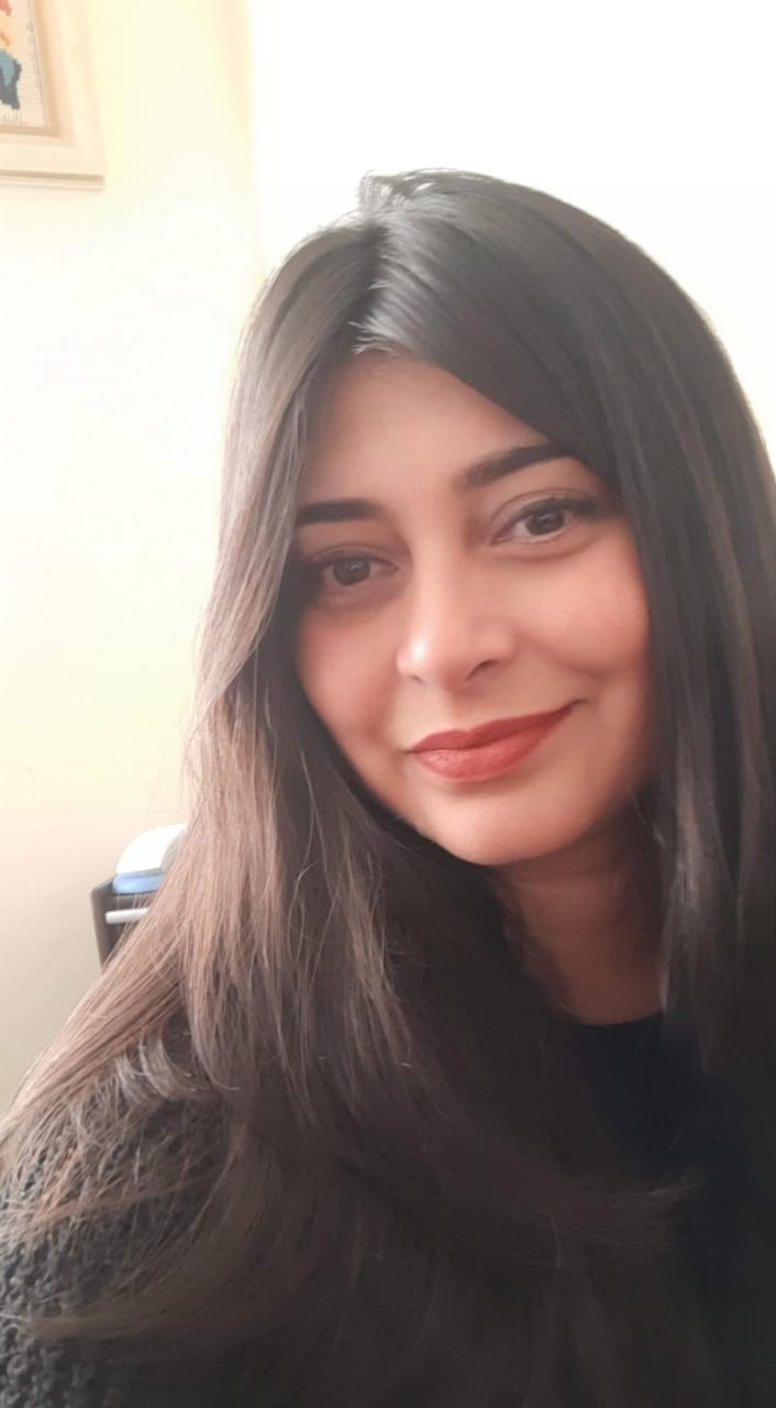 Mulher de cabelos longos e escuros, sorrindo e olhando para a câmera.