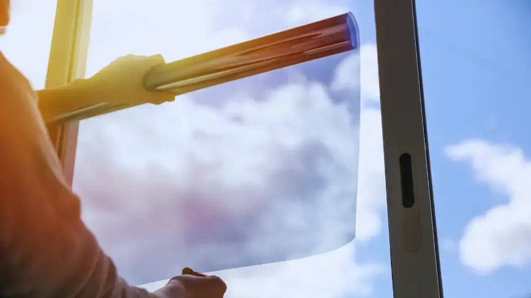 A person is cleaning a window with a squeegee on a sunny day.