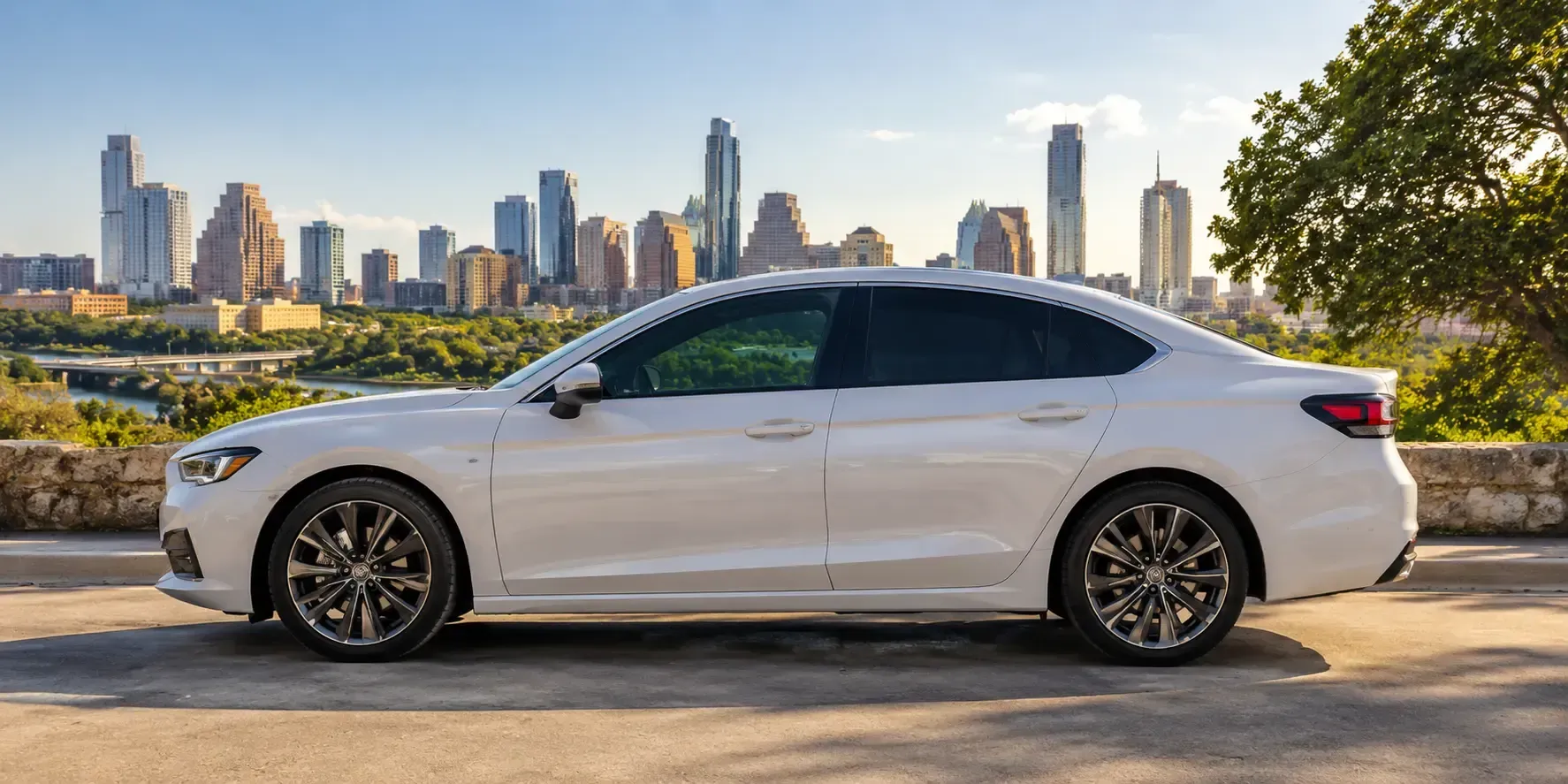 A white sedan with tinted windows parked on a sunny city street, showcasing front and rear window tint in a modern urban setting.