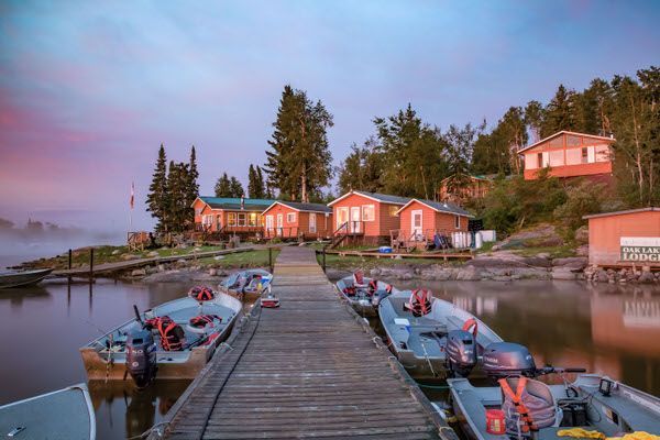A row of boats are docked at a dock on a lake.