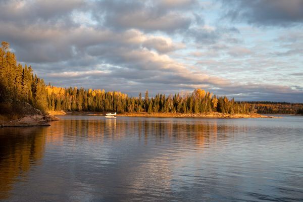A lake with trees on the shore and a boat in the water.