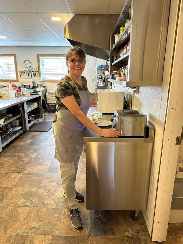 A woman is standing next to a sink in a kitchen.