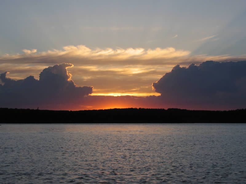 A sunset over a lake with clouds in the sky