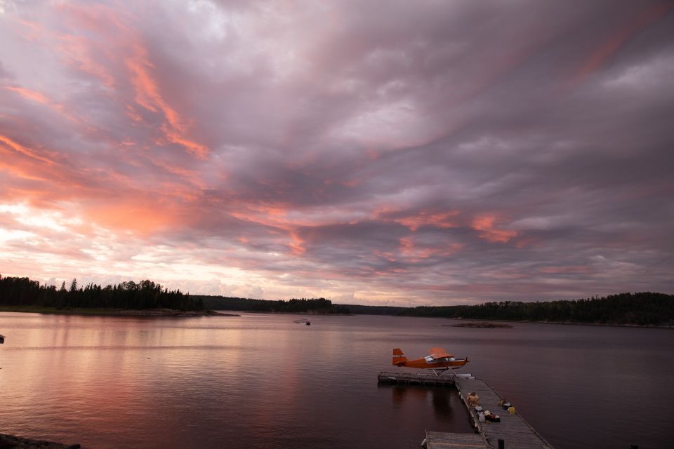 A plane is docked at a dock in the middle of a lake at sunset.