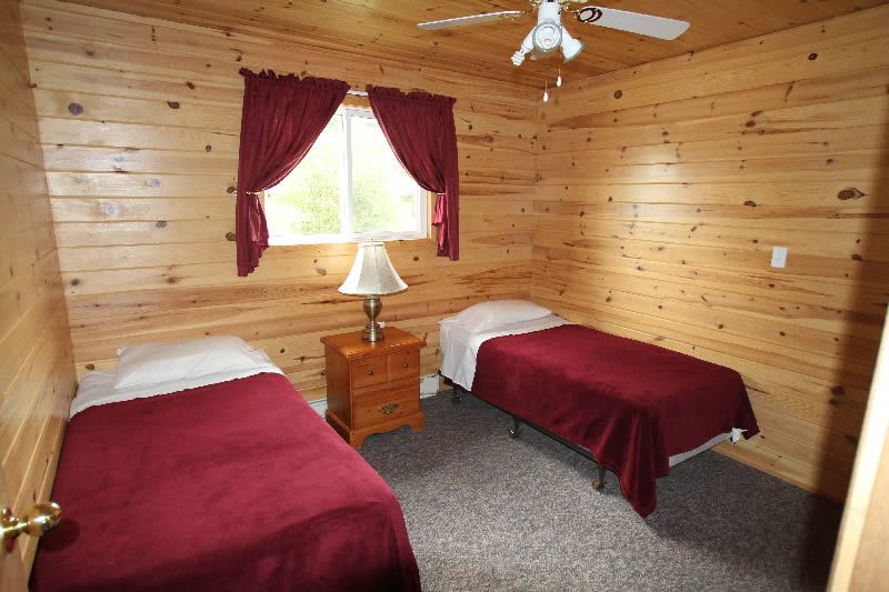 A bedroom with two beds and a ceiling fan