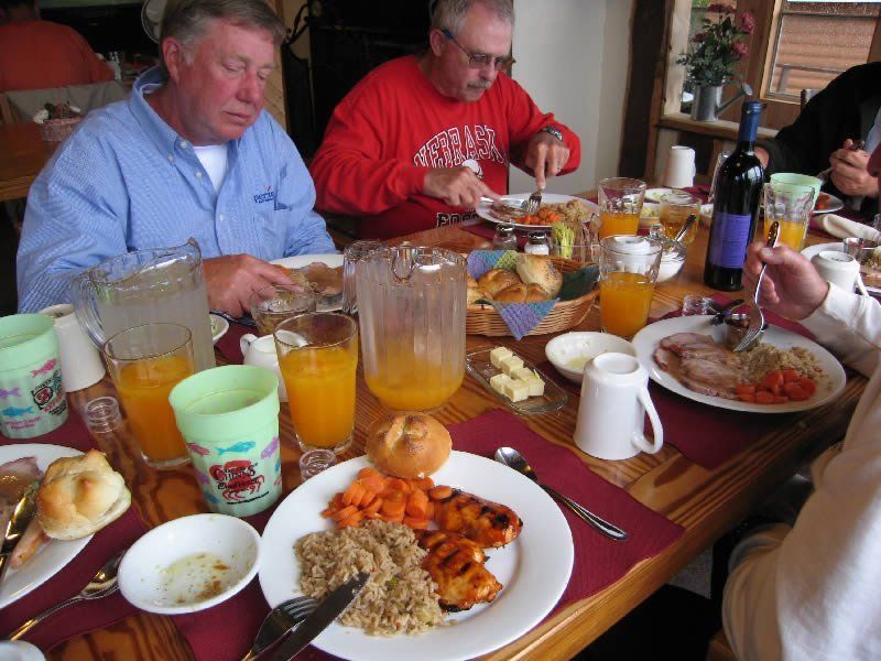 A man in a red shirt is sitting at a table eating food
