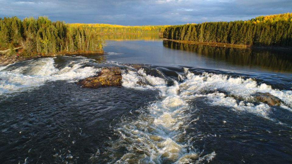 A boat is going down a river with a waterfall in the background.