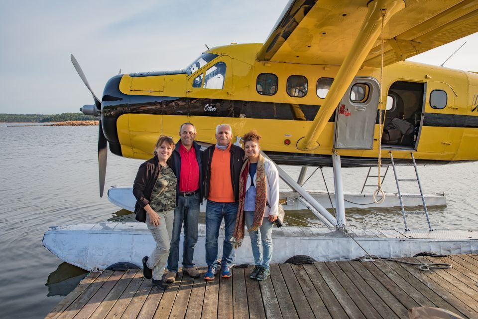 A group of people are posing for a picture in front of a yellow seaplane.