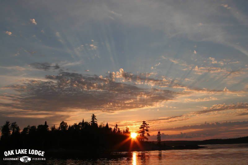 A sunset over a lake with oak lake lodge written on the bottom