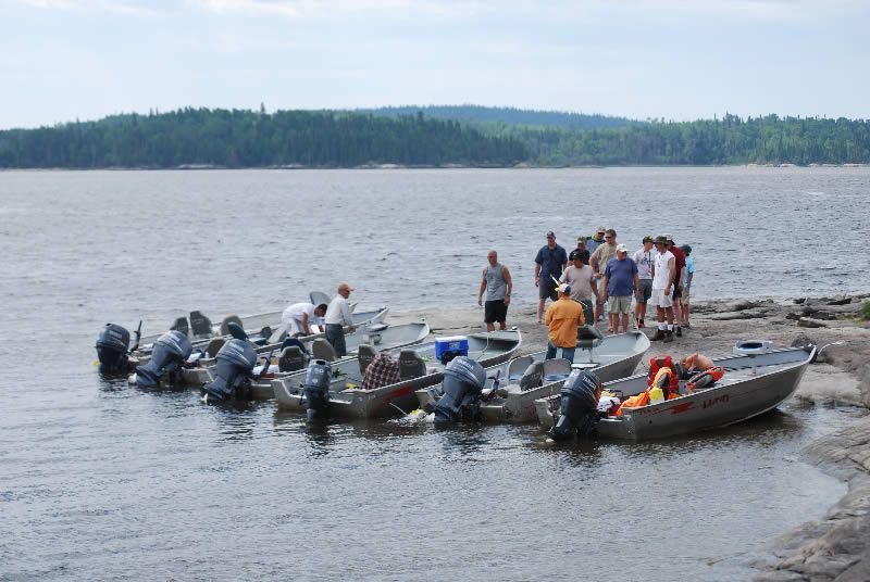 A group of people are standing around boats in the water