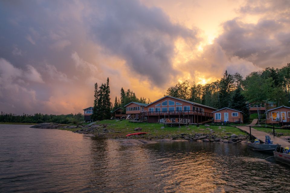 A large house is sitting on the shore of a lake at sunset.