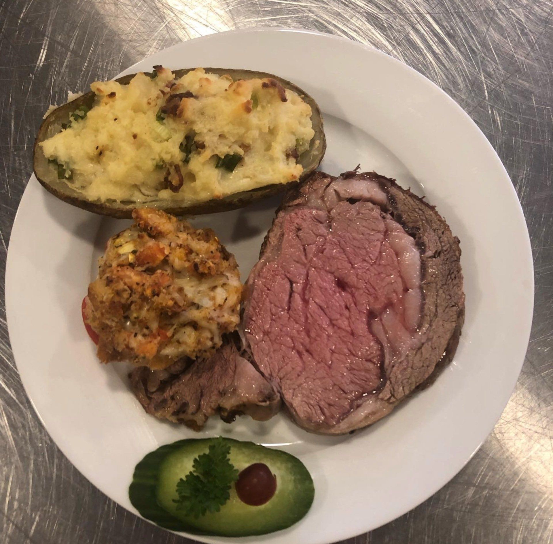 A white plate topped with meat and potatoes on a table