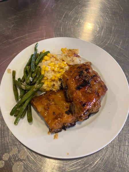 A white plate topped with chicken , green beans , corn and mashed potatoes.