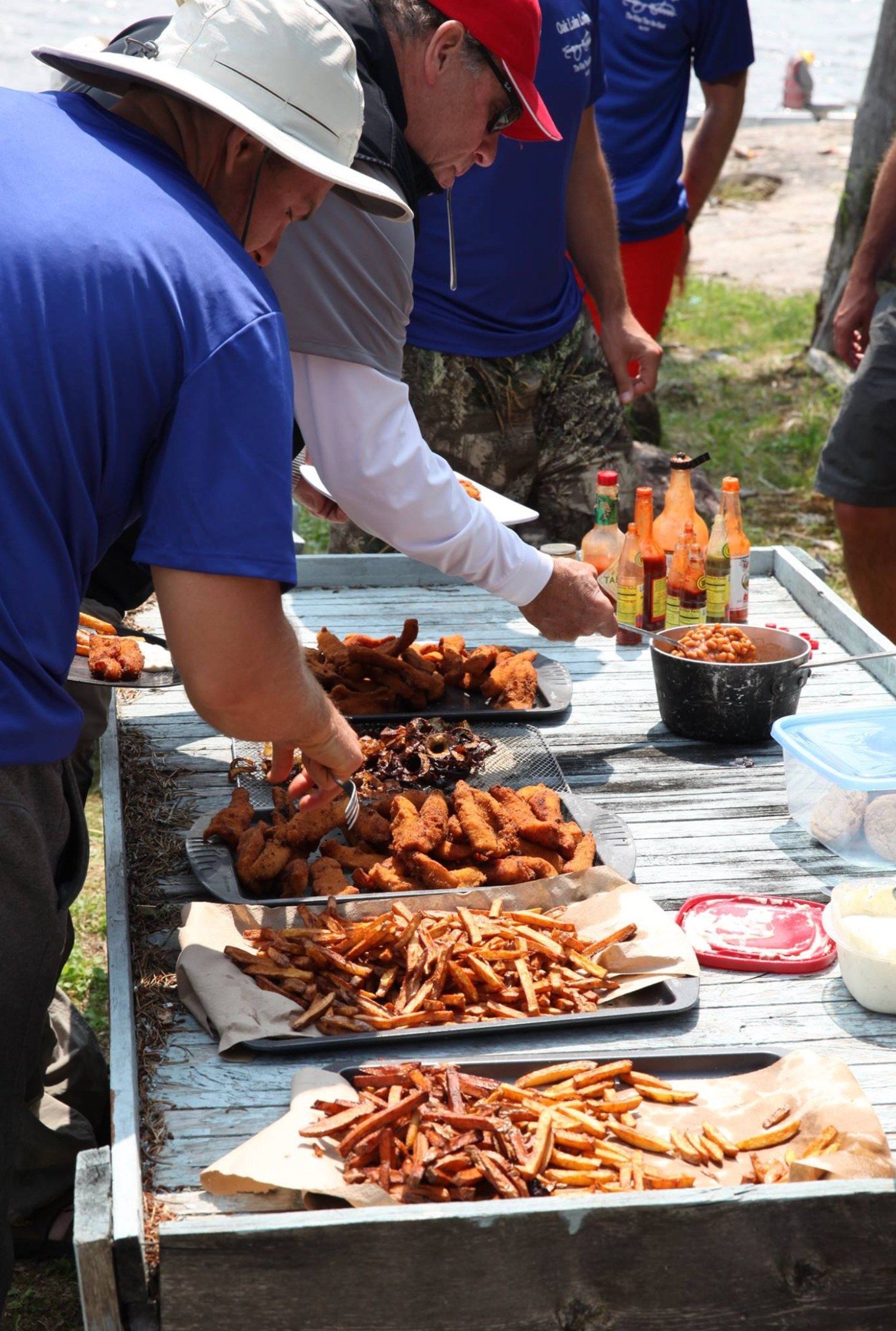 A group of men are standing around a table with trays of food on it