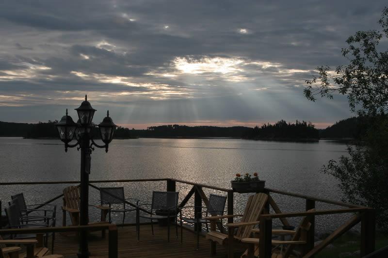 The sun is shining through the clouds over a lake