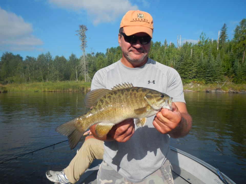 A man in a boat is holding a large  smallmouth bass 