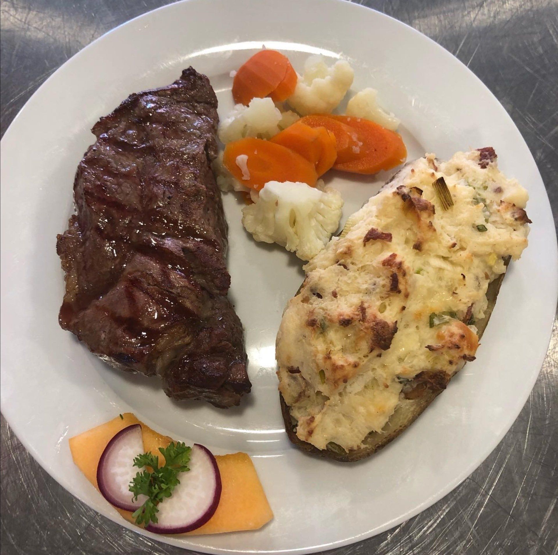 A white plate topped with meat and vegetables on a table