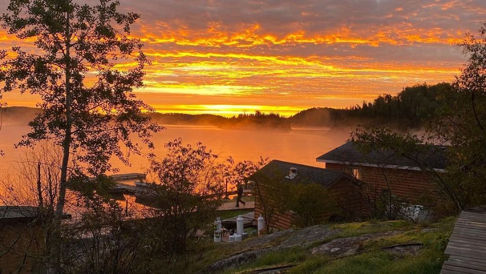A sunset over a lake with a house in the foreground.