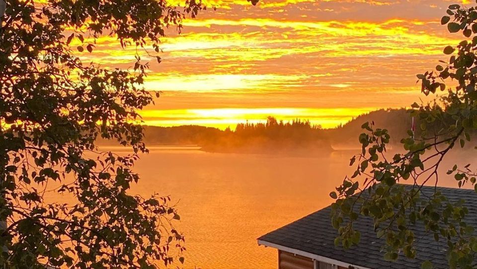 A sunset over a lake with a house in the foreground