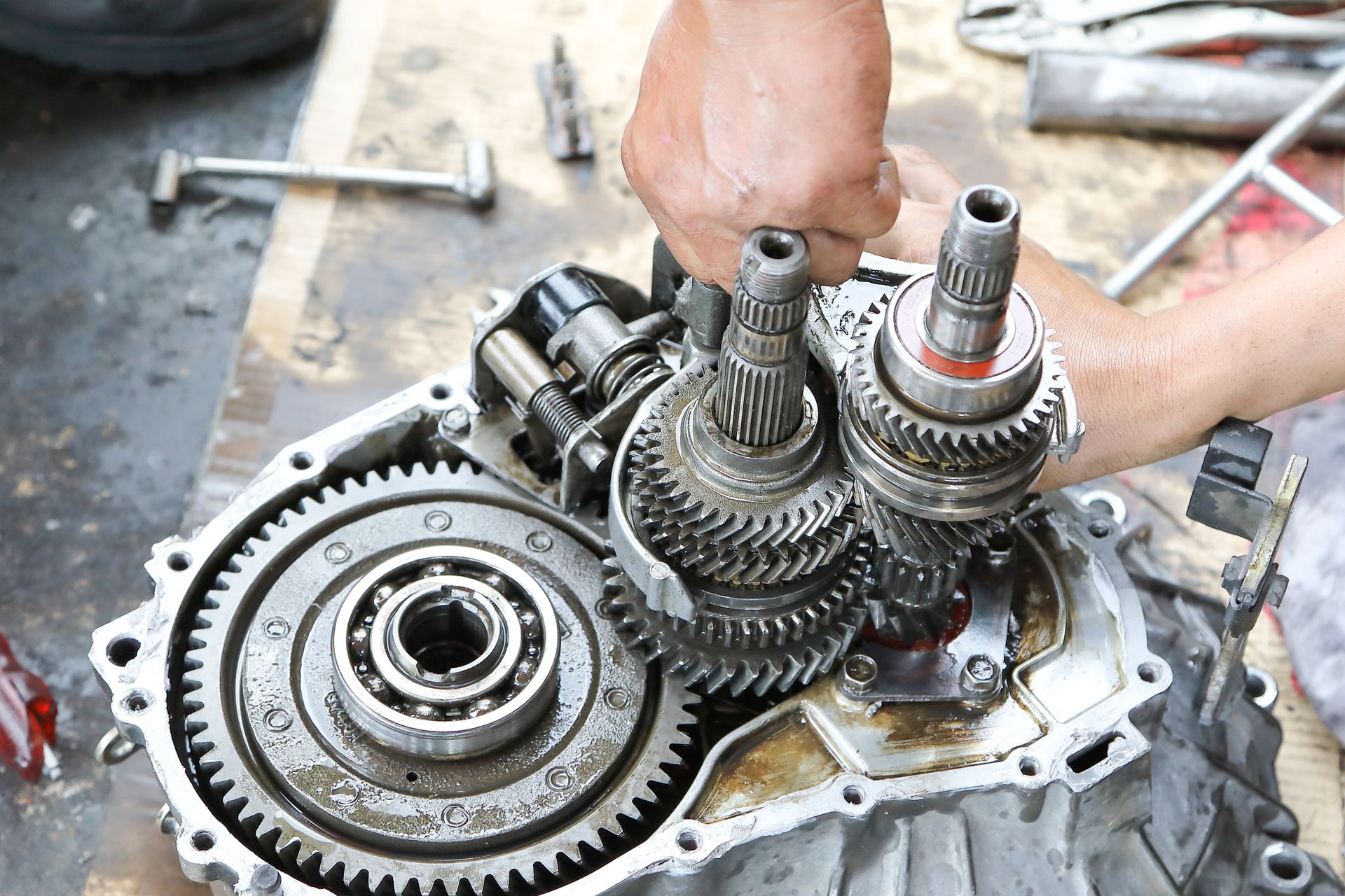 Hand working on an open car transmission with various gears and bearings visible. Hand working on an open car transmission with various gears and bearings visible.