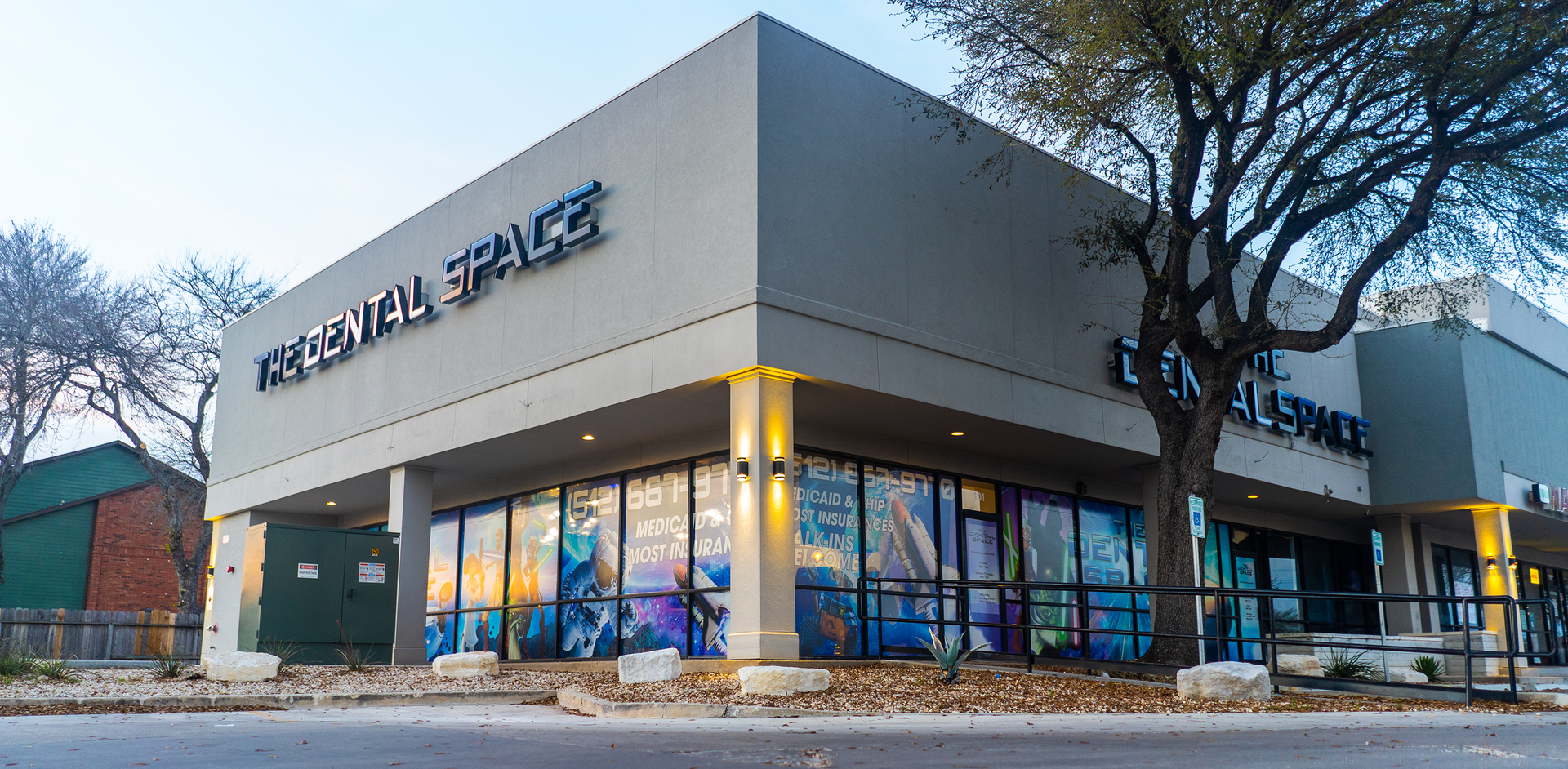 Exterior of an Albertsons store with corner windows, mural panels, and leafless trees