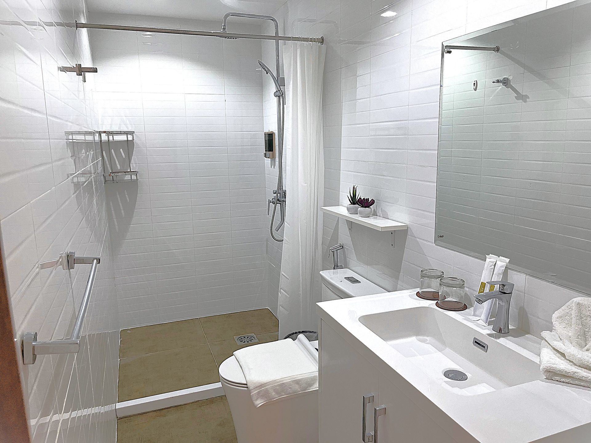 A bathroom with a toilet , sink , mirror and shower.