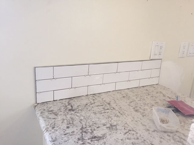 Kitchen backsplash under installation with white subway tiles and unfinished countertop