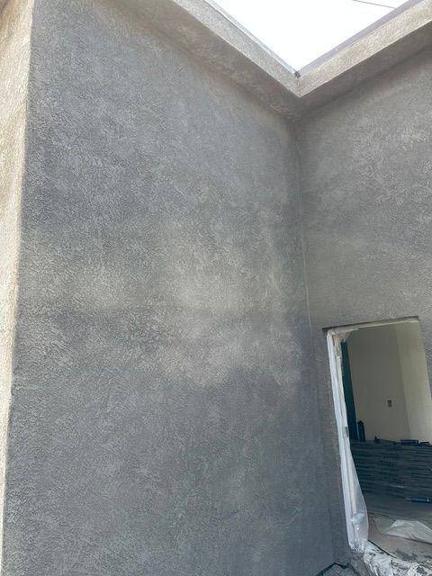 Unfinished gray plaster walls around a small doorway in a room under construction