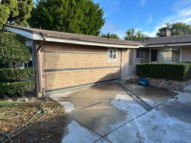 Driveway and garage of a suburban home with wet concrete and trimmed hedges.