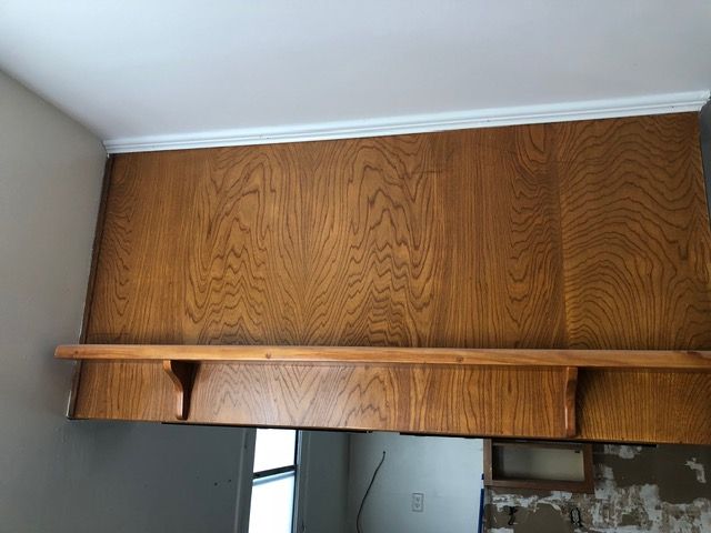 Wooden wall cabinet with crown molding above a doorway in a room