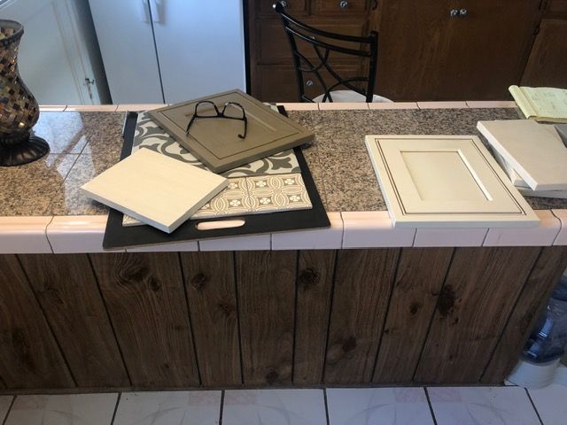 Kitchen counter with sample cabinet doors, tiles, and a folded cloth laid out for home design selection