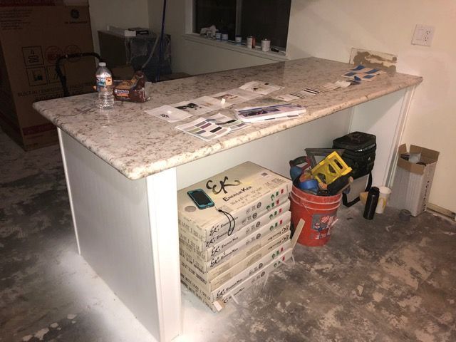 Kitchen island with granite countertop in an unfinished room, with tools and supplies stored underneath.