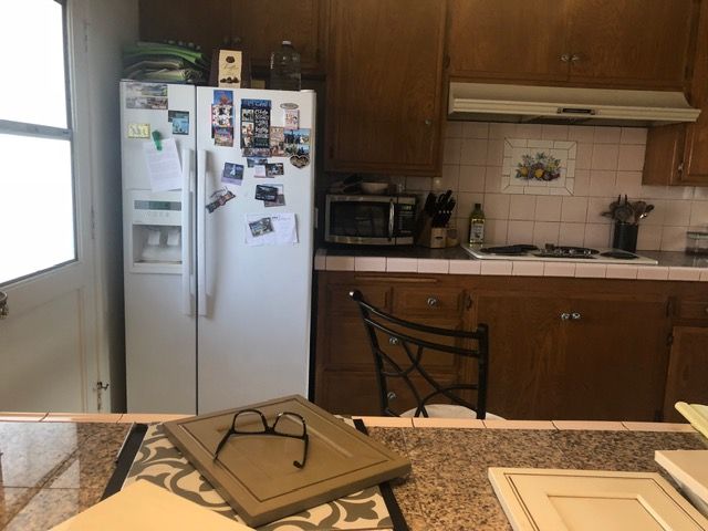 Kitchen with white refrigerator, wooden cabinets, countertop, and table in foreground